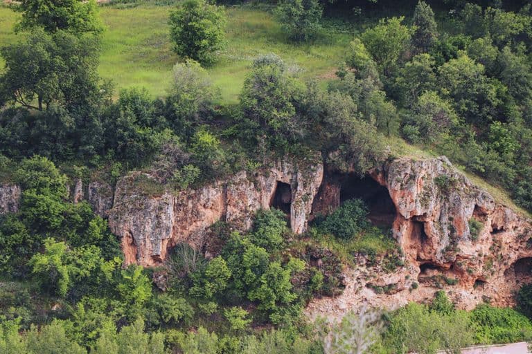 Cueva natural en un paisaje montañoso rodeado de vegetación.
